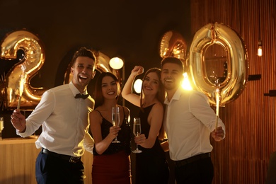 Young people celebrating New Year in club. Golden 2020 balloons on background