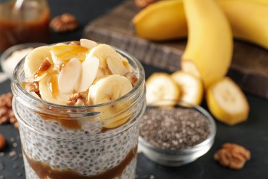 Delicious chia pudding with banana, walnuts and caramel sauce in glass on table, closeup. Space for text