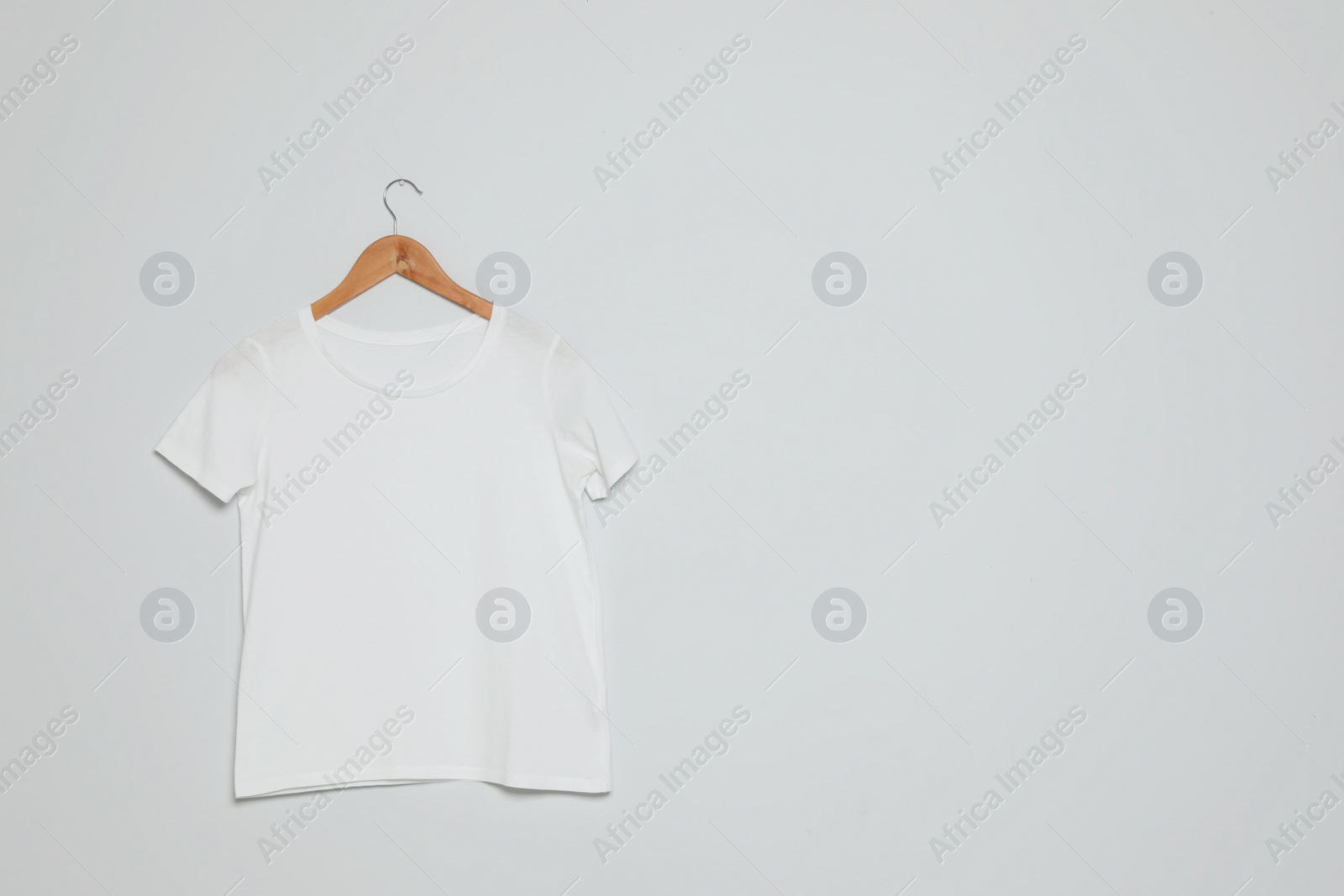 Photo of Hanger with blank t-shirt on gray background. Mock up for design