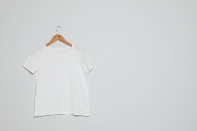 Photo of Hanger with blank t-shirt on gray background. Mock up for design