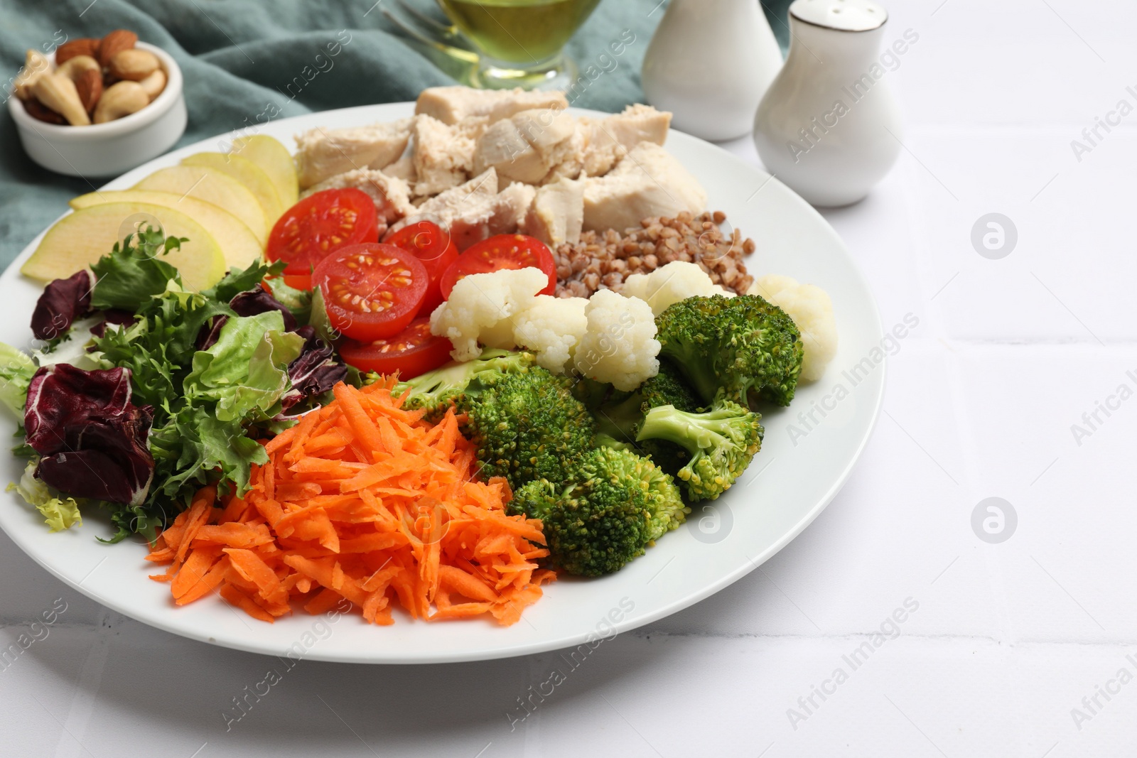 Photo of Balanced diet and healthy foods. Plate with different delicious products on white tiled table, closeup