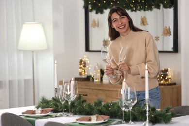 Smiling woman setting table for Christmas celebration at home. Space for text