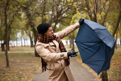 Photo of Man with blue umbrella caught in gust of wind outdoors