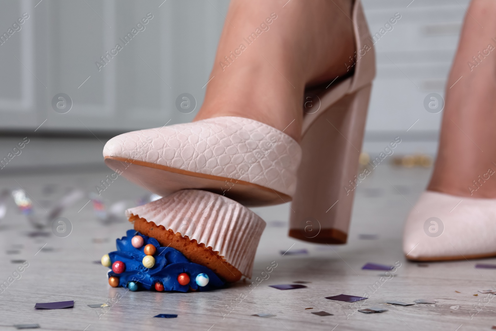 Photo of Woman stepping on dropped cupcake indoors, closeup. Troubles happen