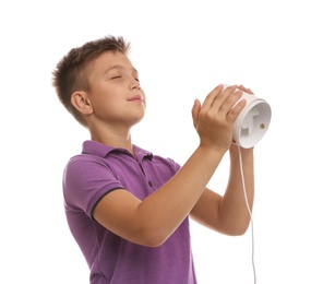 Photo of Little boy enjoying air flow from portable fan on white background. Summer heat