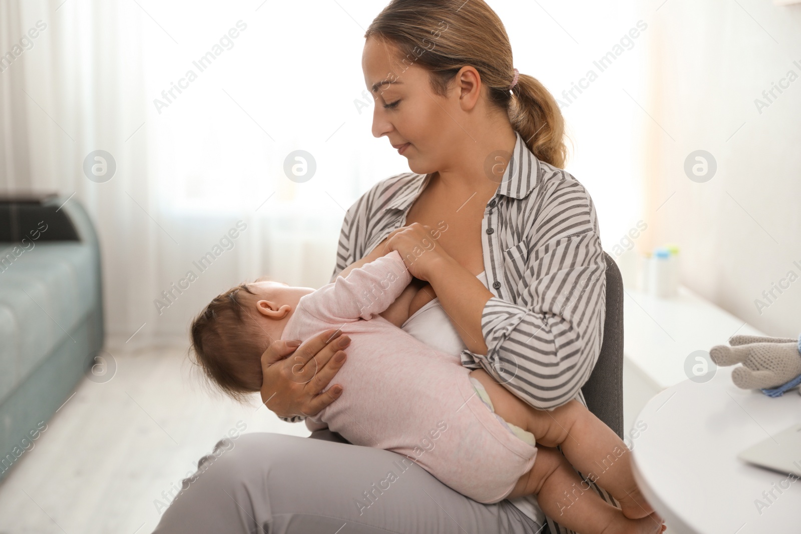 Photo of Young woman breastfeeding her baby at home