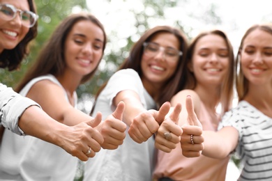 Photo of Happy women showing thumbs up outdoors, focus of hands. Girl power concept