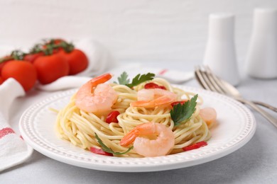 Tasty spaghetti with shrimps, chili pepper and parsley on grey table, closeup