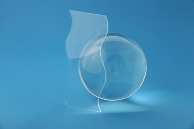 Photo of Composition with transparent glass ball on blue background
