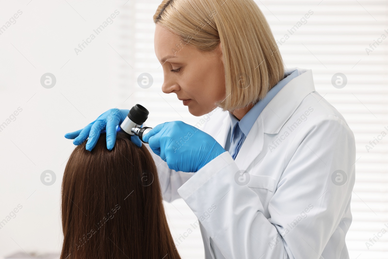 Photo of Trichologist with dermatoscope examining patient`s hair in clinic