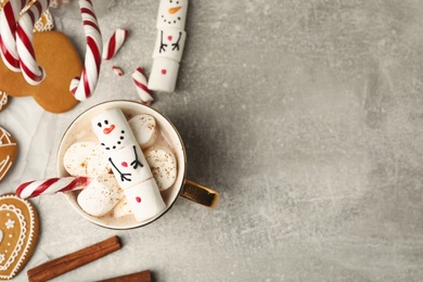 Flat lay composition with funny snowman made of marshmallows on grey table. Space for text