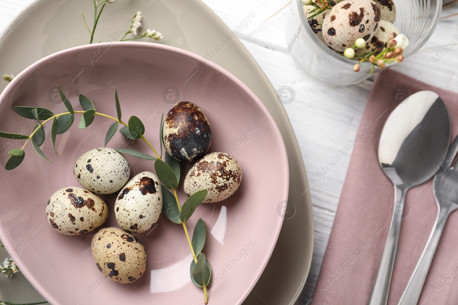 Photo of Festive Easter table setting with quail eggs and floral decoration on wooden background, flat lay