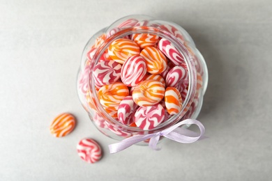 Photo of Sweet candies in glass jar on light grey table, flat lay