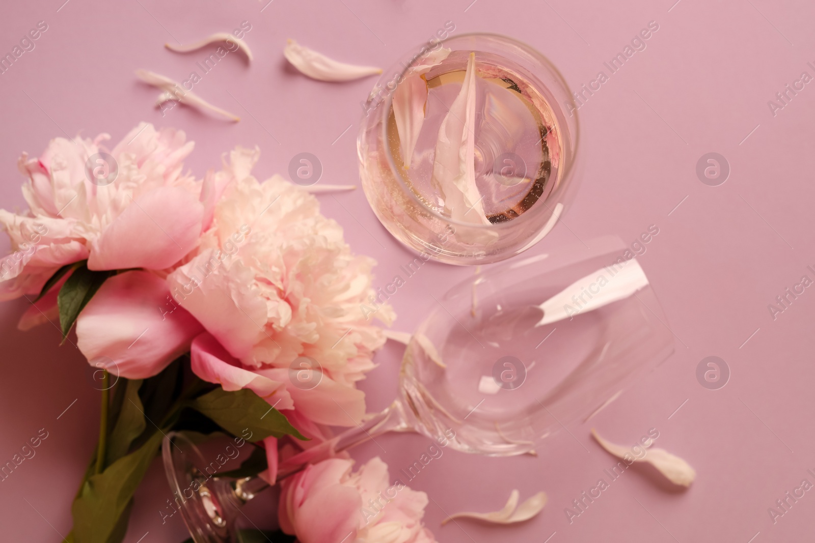 Photo of Flat lay composition with rose wine, glasses and beautiful peonies on pink background