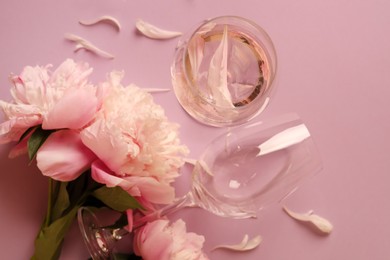 Photo of Flat lay composition with rose wine, glasses and beautiful peonies on pink background