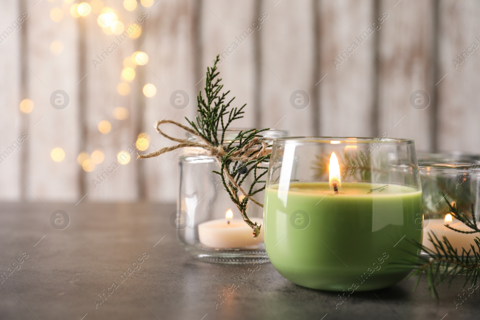 Photo of Burning candle with pinecone scent on black table, space for text