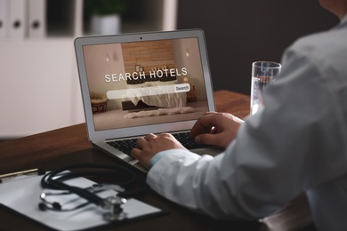 Image of Doctor searching hotel using laptop at table, closeup. Booking online service