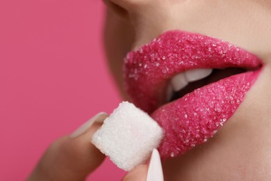 Photo of Closeup view of young woman with beautiful lips holding sugar cube on pink background