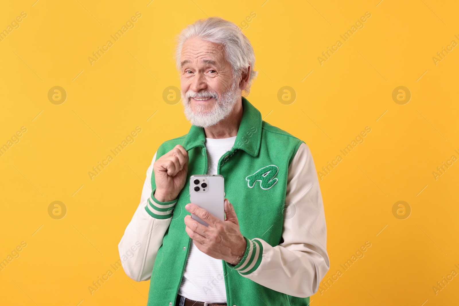 Photo of Portrait of stylish grandpa using smartphone on yellow background