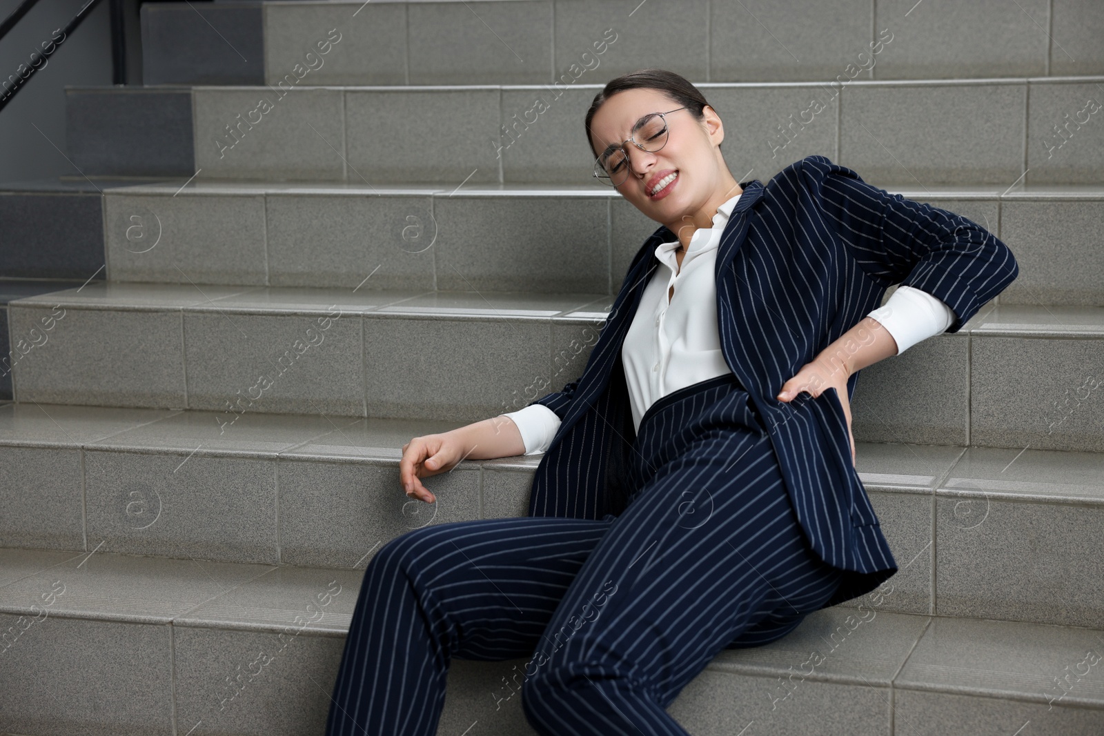 Photo of Woman fallen down stairs suffering from pain in back indoors