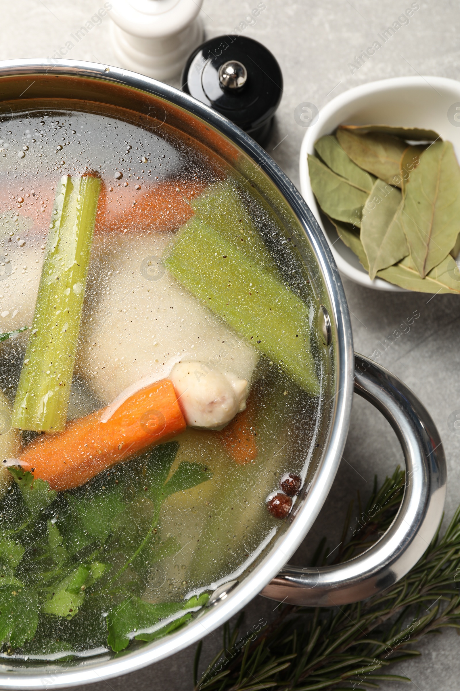 Photo of Pot with tasty bouillon on light grey table, flat lay