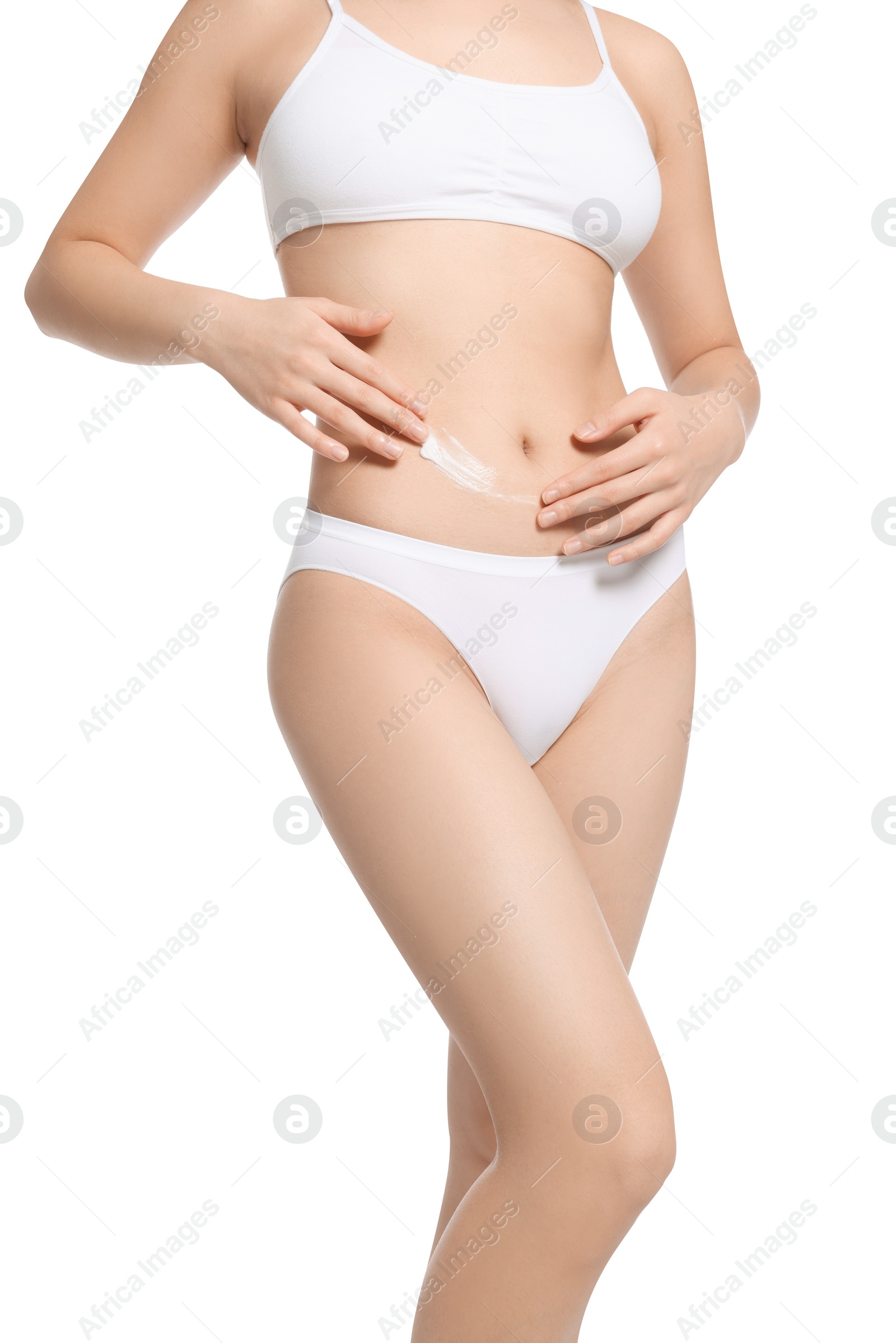 Photo of Young woman with body cream smear on belly against white background, closeup