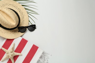 Beach towel, straw hat and sunglasses on light background, flat lay. Space for text