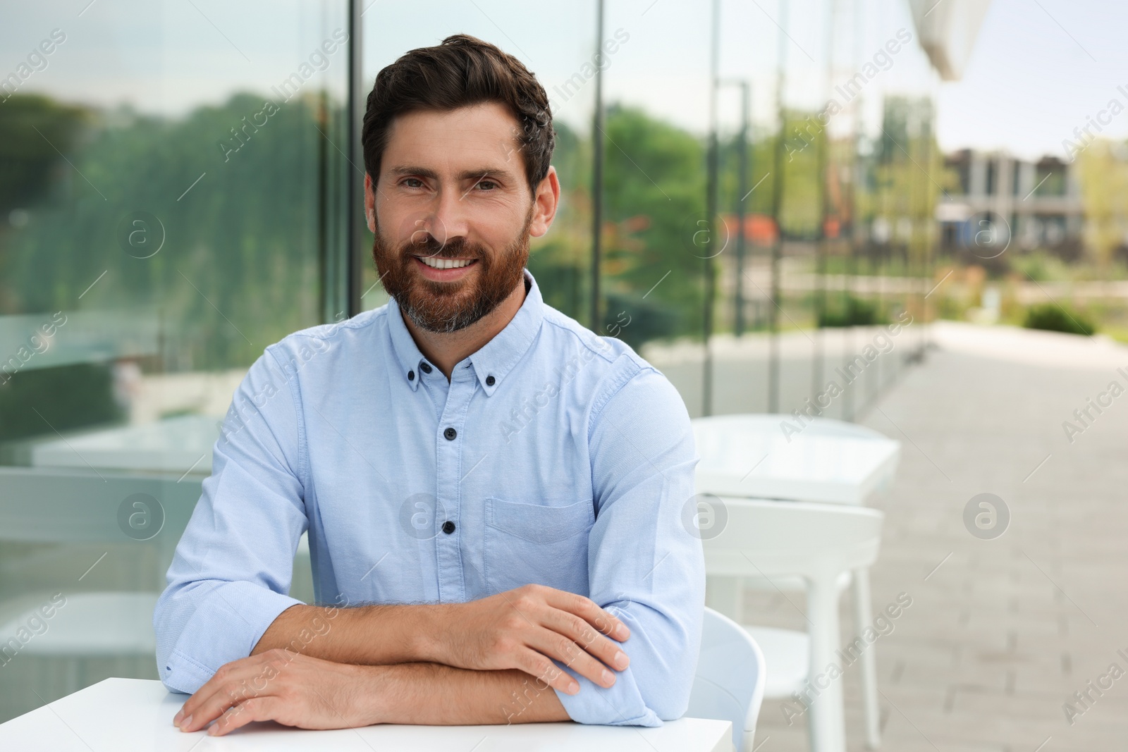 Photo of Portrait of handsome bearded man in outdoor cafe, space for text