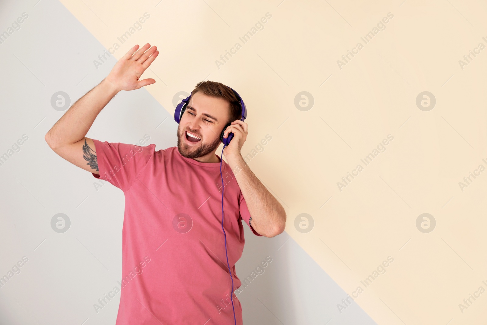 Photo of Handsome man enjoying music in headphones on color background. Space for text