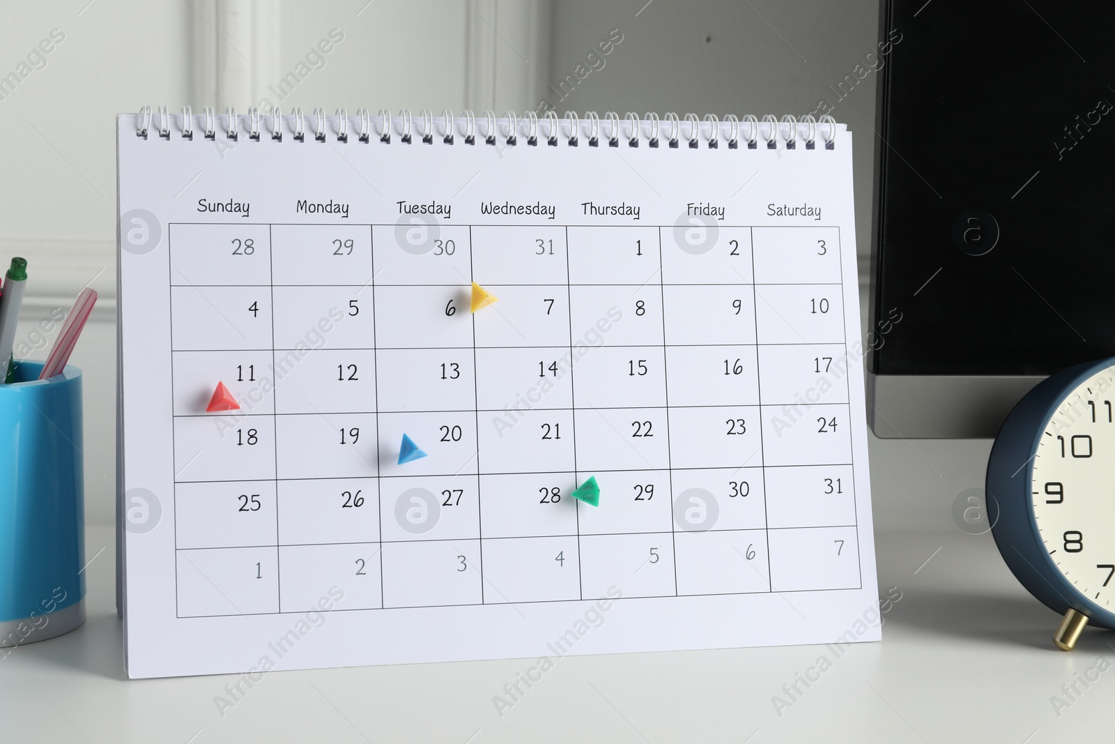 Photo of Timetable. Calendar with marked dates, alarm clock and stationery on white table indoors