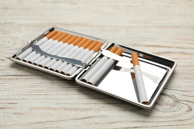 Stylish case with cigarettes on white wooden table