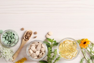 Different pills, flowers and herbs on white wooden table, flat lay with space for text. Dietary supplements