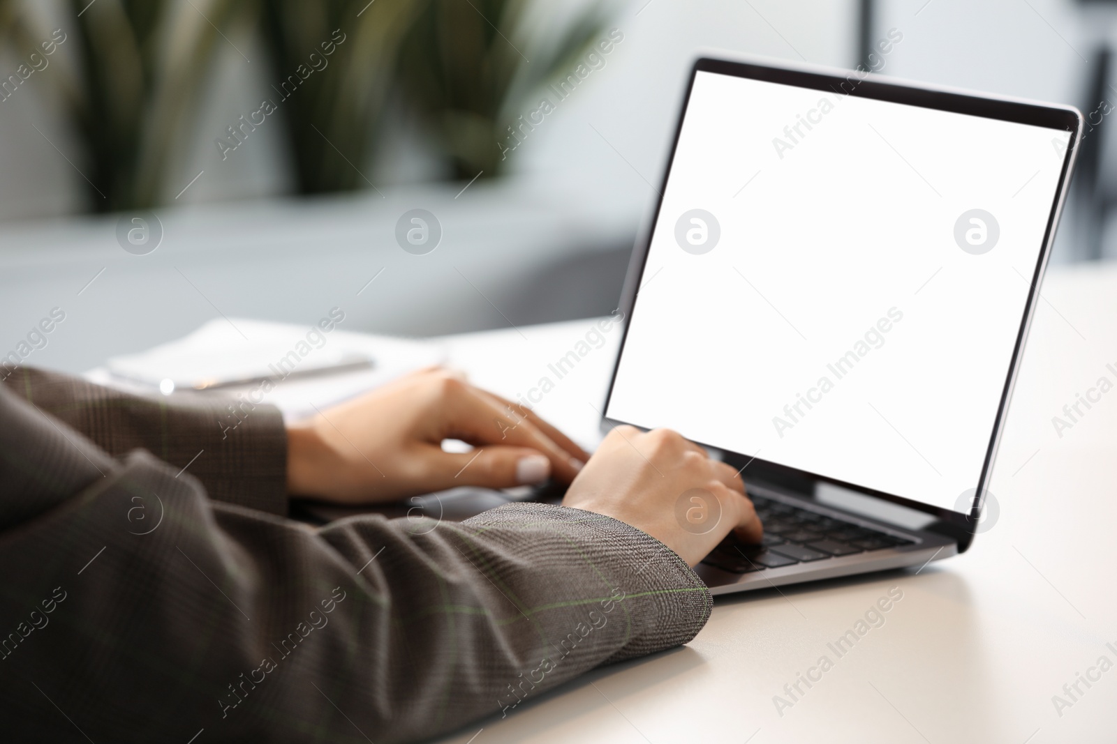 Photo of Woman using modern laptop at desk in office, closeup