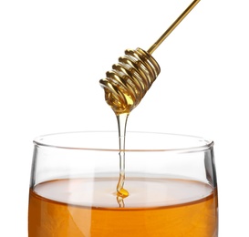 Honey dripping from dipper into jar on white background