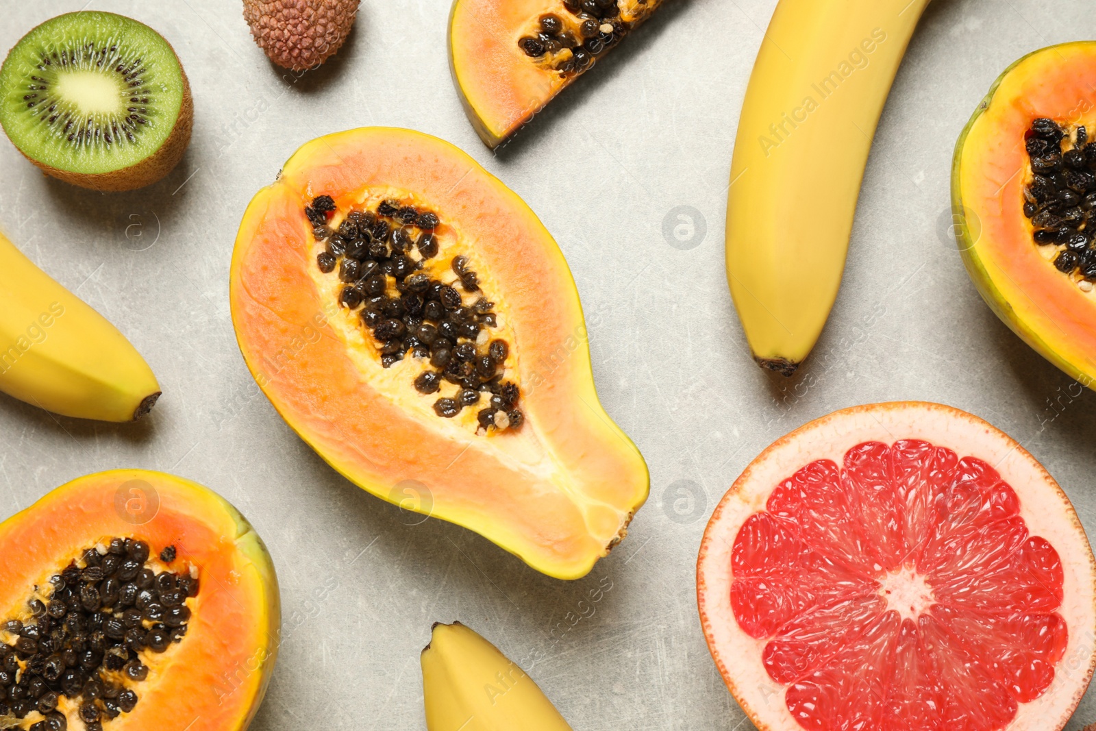 Photo of Fresh ripe papaya and other fruits on light grey table, flat lay