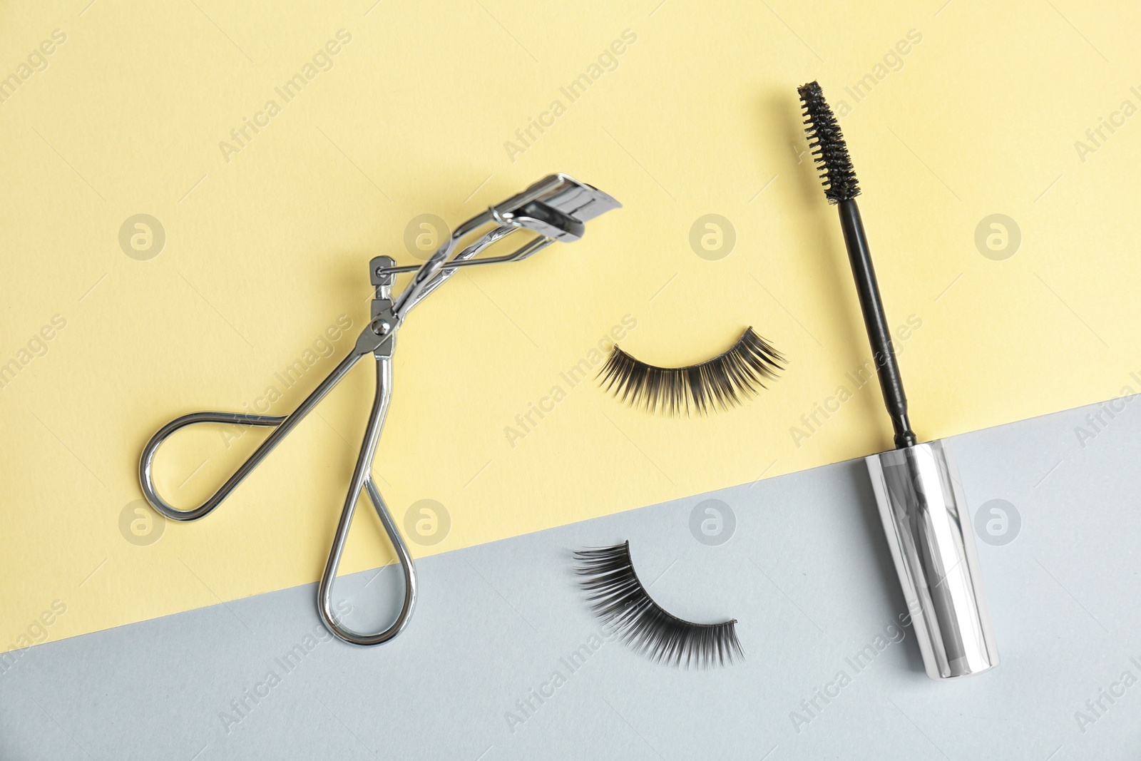 Photo of False eyelashes, curler and mascara brush on color background, flat lay