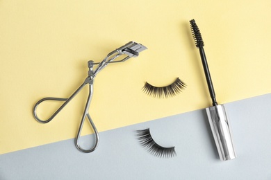 False eyelashes, curler and mascara brush on color background, flat lay