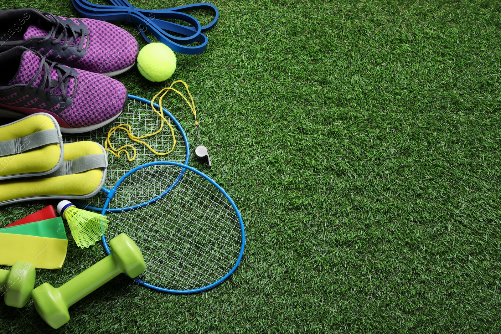 Photo of Set of different colorful sports equipment on green grass, above view. Space for text