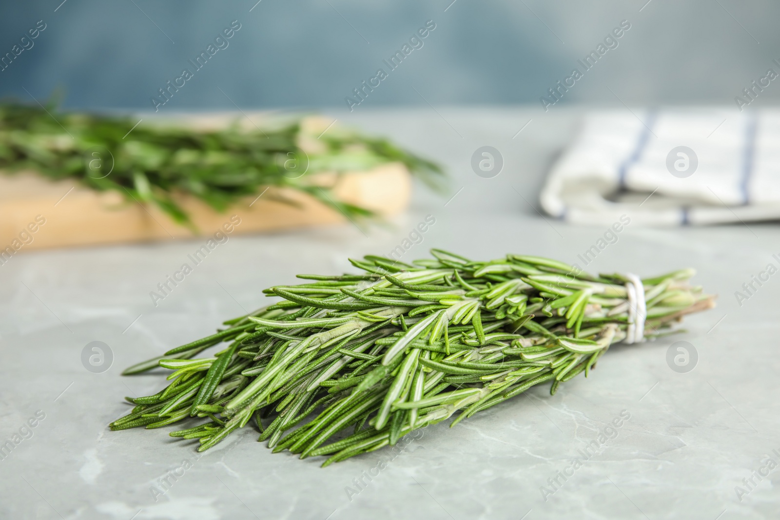 Photo of Bunch of fresh rosemary on grey marble table