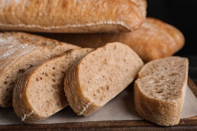 Photo of Wooden board with cut delicious ciabattas, closeup