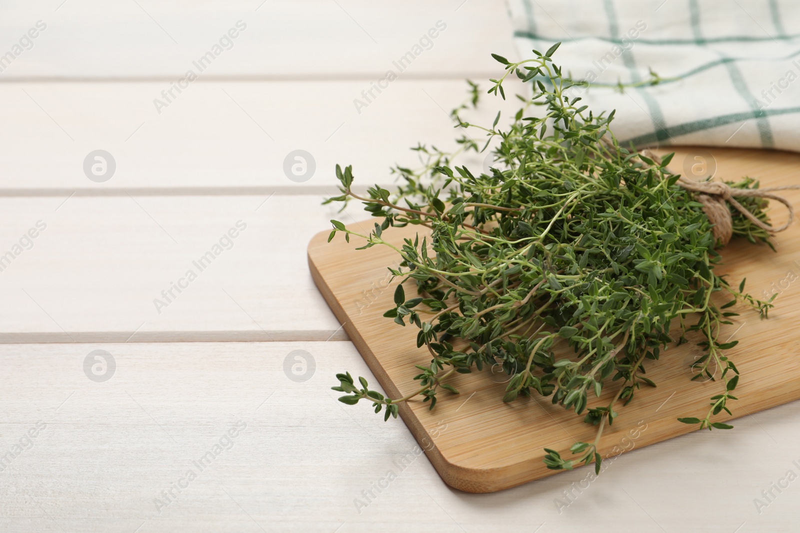 Photo of Bunch of aromatic thyme on white wooden table, closeup. Space for text