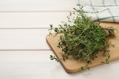 Bunch of aromatic thyme on white wooden table, closeup. Space for text