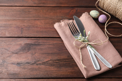 Photo of Cutlery set with quail eggs on wooden table, space for text. Easter celebration