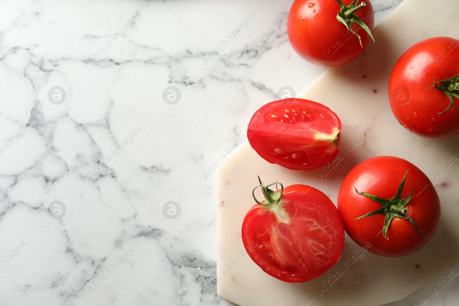 Photo of Fresh ripe tomatoes on white marble table, flat lay. Space for text