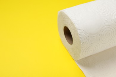 Photo of Roll of paper towels on yellow background, closeup. Space for text