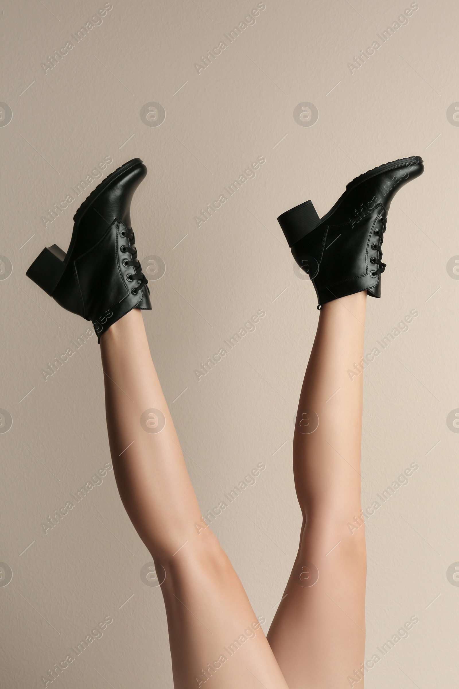 Photo of Woman wearing stylish boots on beige background, closeup