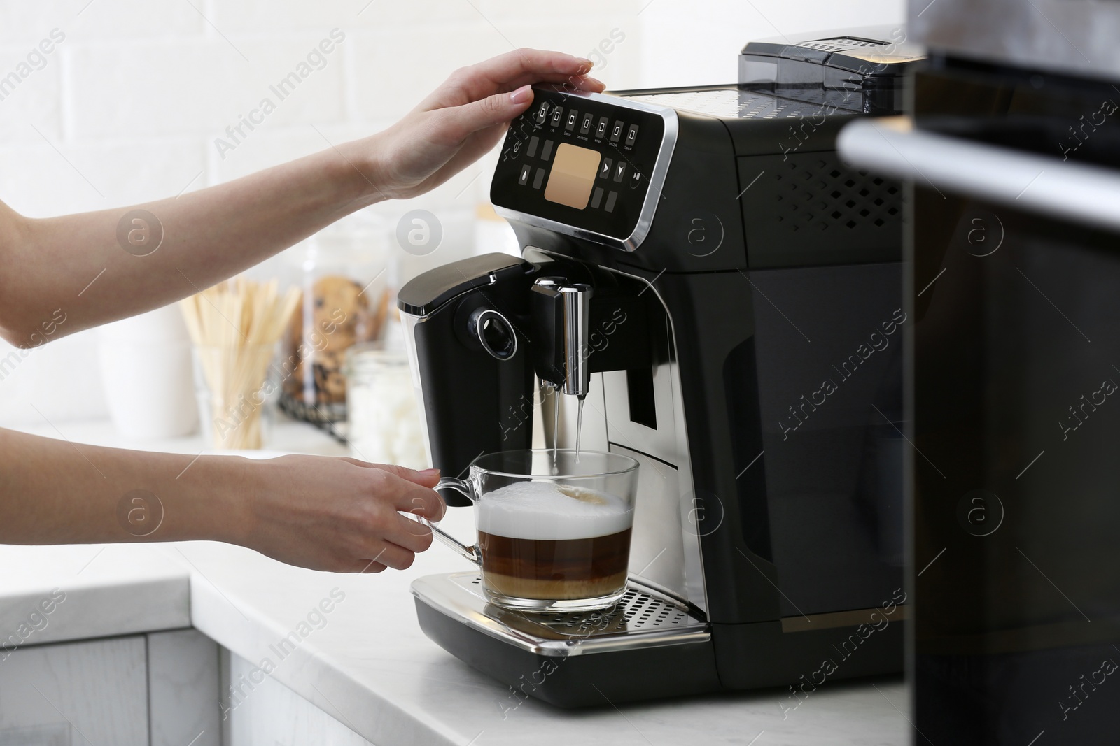 Photo of Woman using modern espresso machine for making coffee with milk in kitchen, closeup
