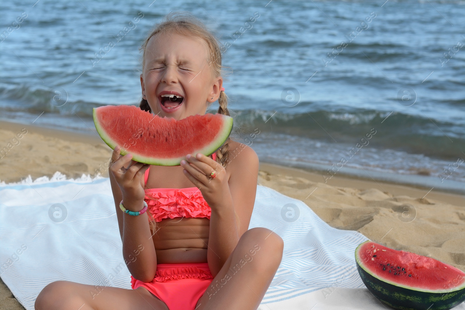 Photo of Cute little girl eating juicy watermelon on beach