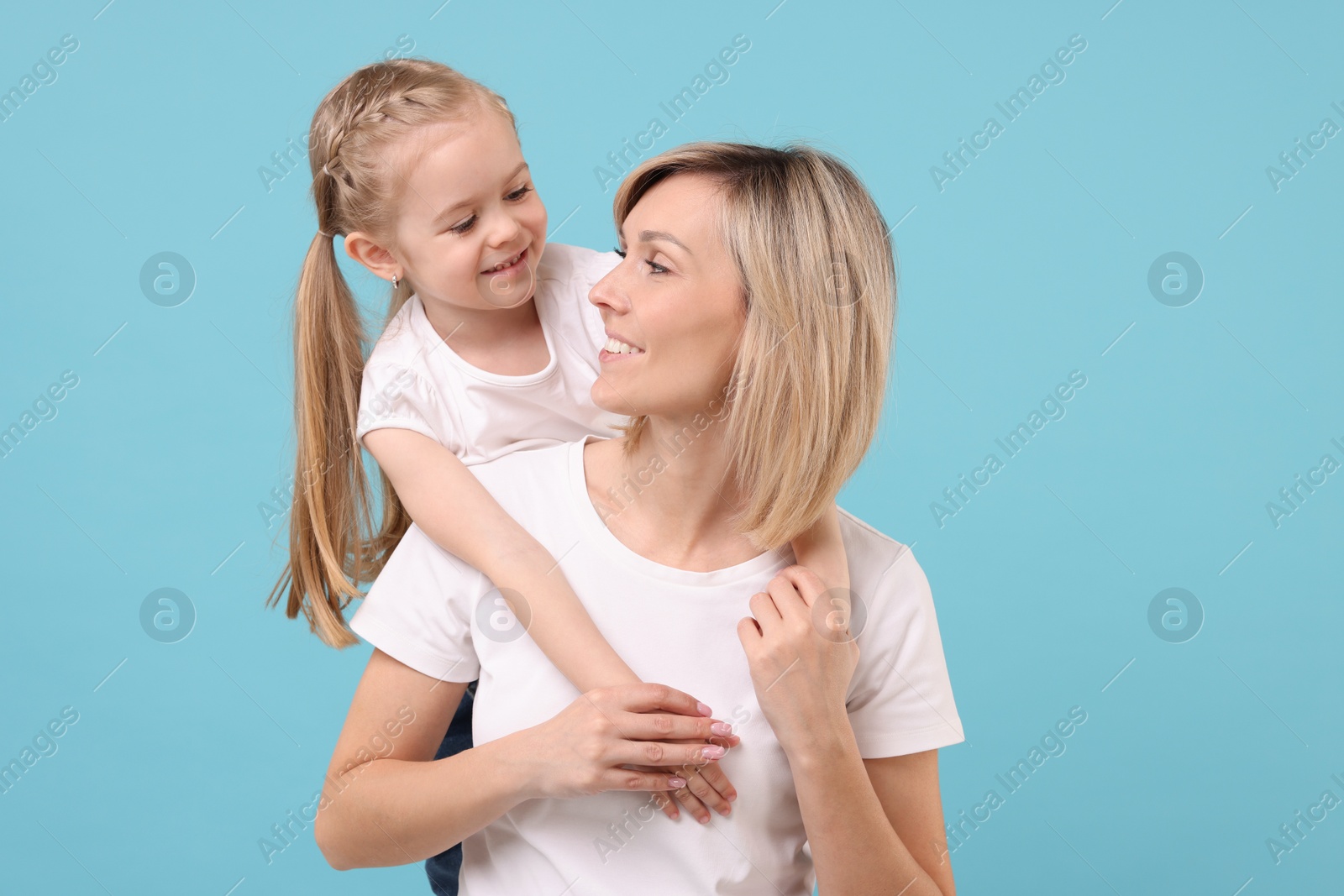 Photo of Family portrait of happy mother and daughter on light blue background