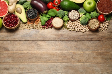 Different vegetables, seeds and fruits on wooden table, flat lay with space for text. Healthy diet